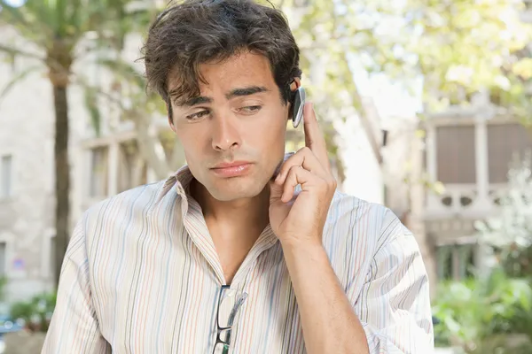Affärsman med en händerna fria enhet ha ett samtal på sin mobiltelefon — Stockfoto