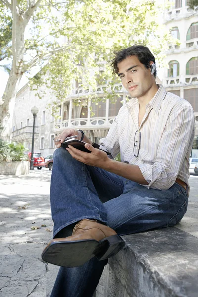 Affärsman med hjälp av en mobiltelefon örat bit för att tala i telefon — Stockfoto