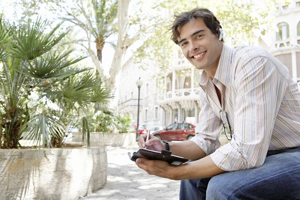 Young businessman using a cell phone's ear piece to speak on the phone — Stock Photo, Image