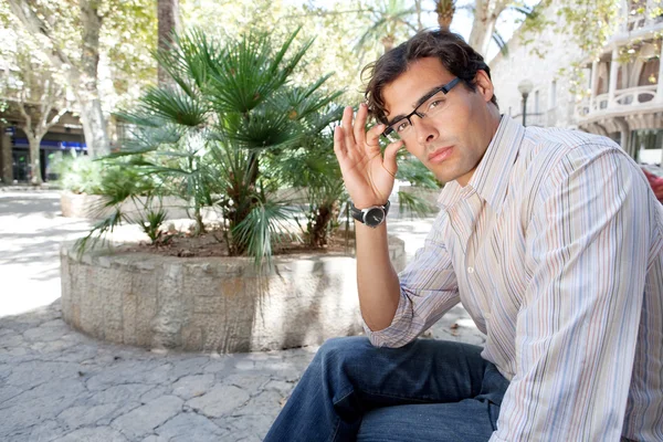 Joven empresario mirando a la cámara mientras sostiene sus gafas de lectura — Foto de Stock