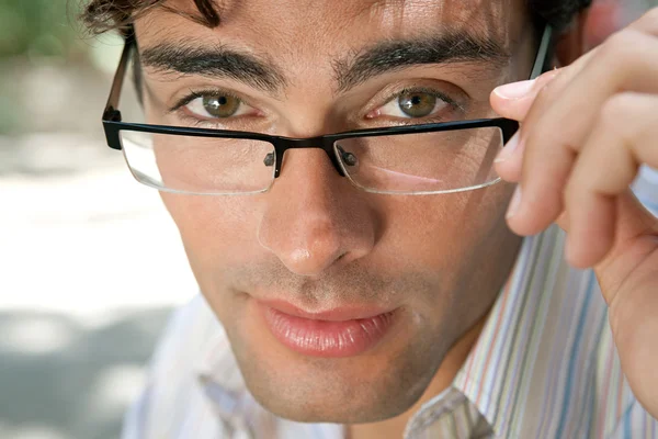 Close up portrait of an attractive businessman wearing glasses and looking at the camera in the city — Stock Photo, Image