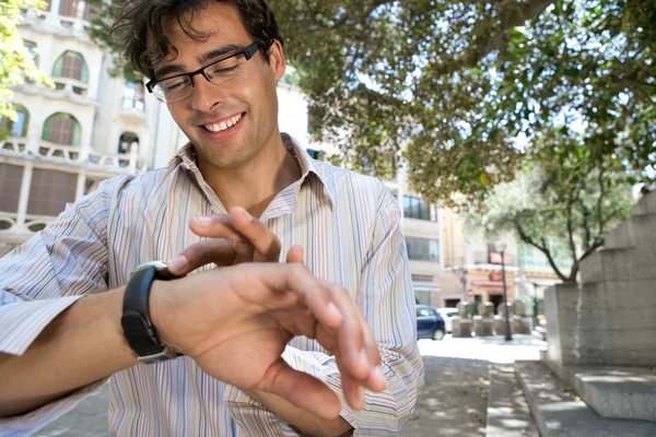 Portrait of a young businessman checking his watch while standing in a classic city exterior. — Stock Photo, Image