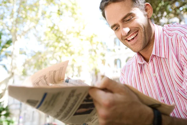 Successful senior businessman reading a financial newspaper while sitting in a classic city square — Stock Photo, Image