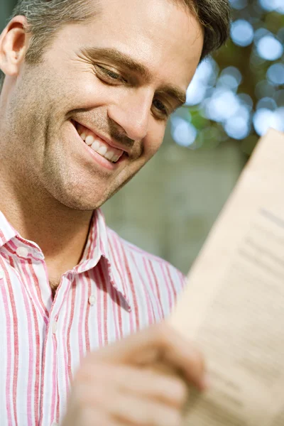 Portrait of a senior businessman reading a financial newspaper while sitting in the city — Stock Photo, Image