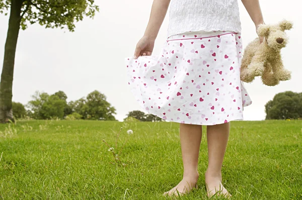 Close up detail of a young girl holding a soft toy in the park, body section. — Stock Photo, Image