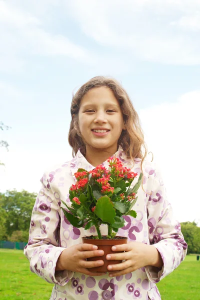 Jeune fille se sentant fière, tenant un pot plan avec des fleurs dans le parc . — Photo