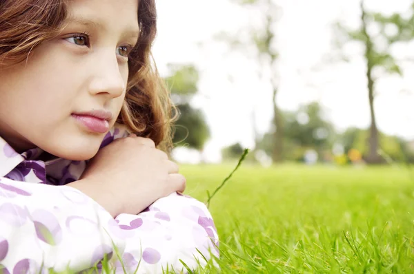 Young girl laying down on green grass in the park — Stock Photo, Image