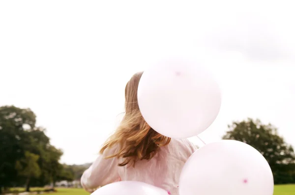 Pohled zezadu na dítě drží balónky v parku. — Stock fotografie
