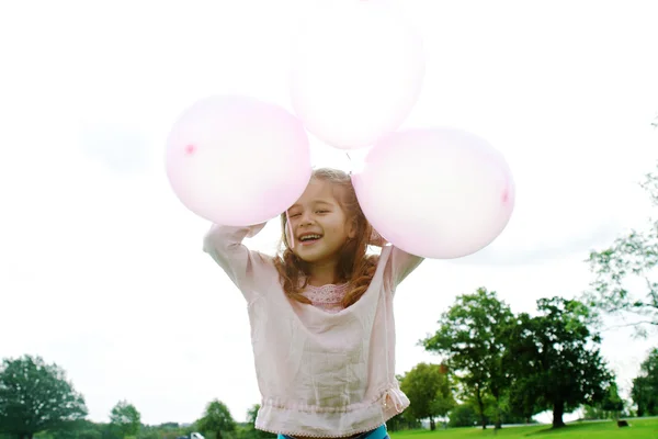 Gülen ve having fun park, üç pembe balonlar tutan genç kız. — Stok fotoğraf