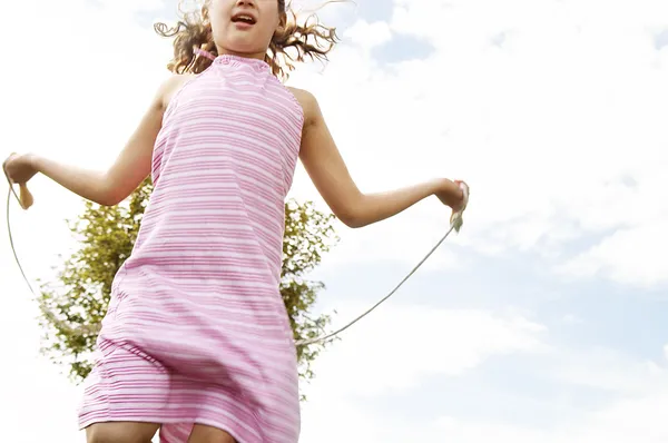 Junges Mädchen hüpft mit Seil im Park. — Stockfoto