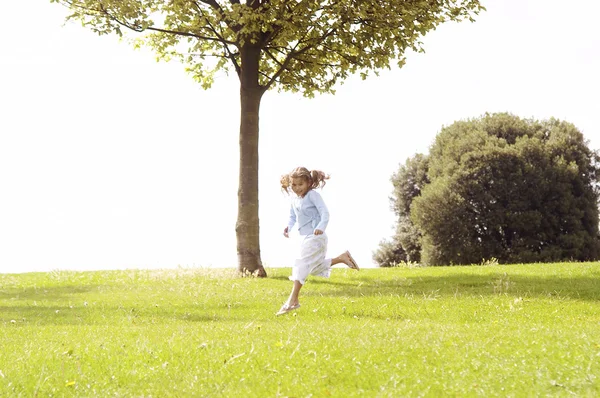 Young girl jumping on a green grass hill. — Stock Photo, Image