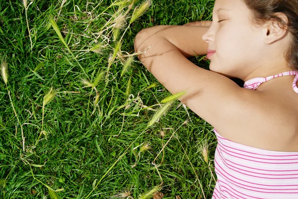 Close up rear view of a young girl sleeping on green grass in the park. — Stock Photo, Image