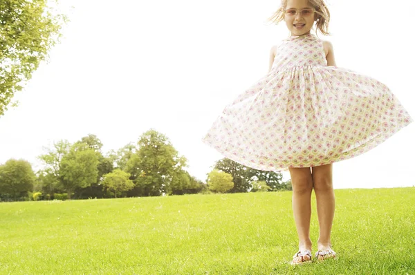 Young girl showing off her dress and wearing pink shades in the park. — Stock Photo, Image