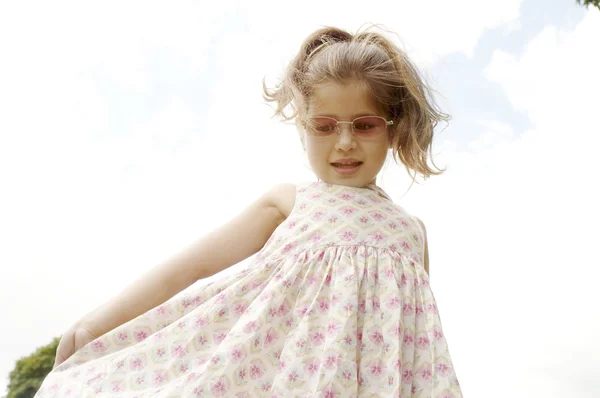 Jong meisje pronken haar jurk en het dragen van roze tinten. — Stockfoto