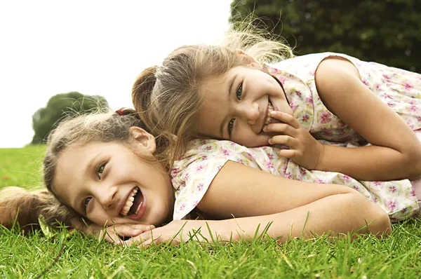 Duas irmãs rindo e brincando no parque Fotos De Bancos De Imagens