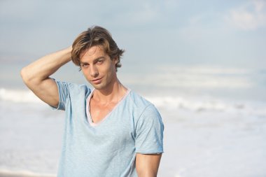 Sahilde deniz arka plan ile çekici bir genç adam.