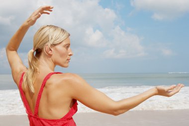 pratik Yoga bir plajda çekici genç bir kadın.