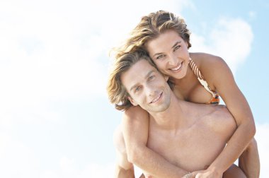 genç adam bir domuzcuk çanta çekici kız, mavi gökyüzü karşı vererek.