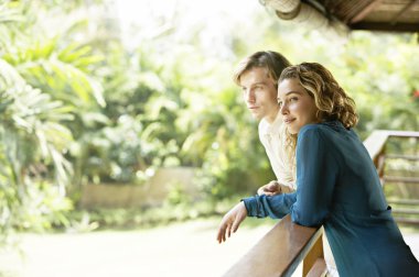young couple on vacations, leaning on a balcony's veranda
