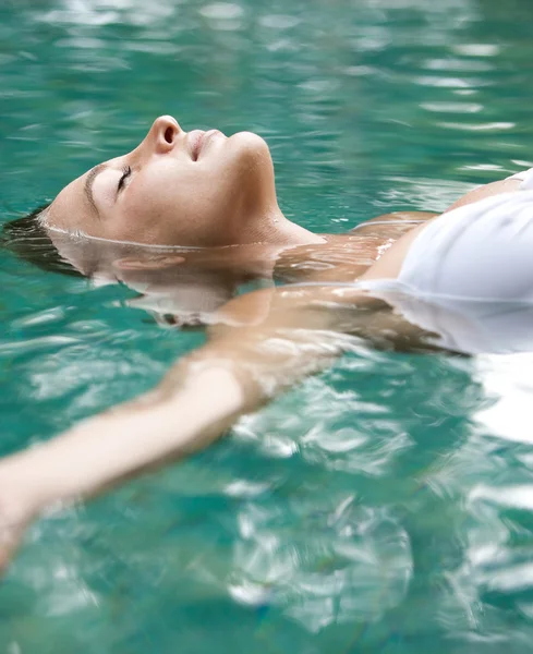 Aantrekkelijke jonge vrouw drijvend op een spa zwembad — Stockfoto