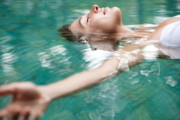 attractive young woman floating on a spa's swimming pool.