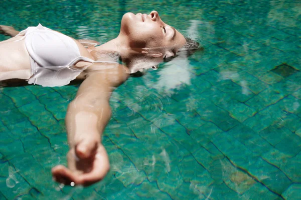 水に浮かんでいるスイミング プールで休暇中の若い女性. — ストック写真