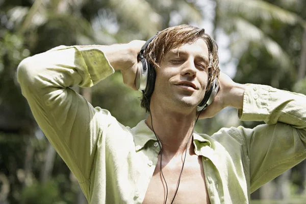 mutlu bir adam bir tropik bahçe kulaklık ile müzik dinlemek.