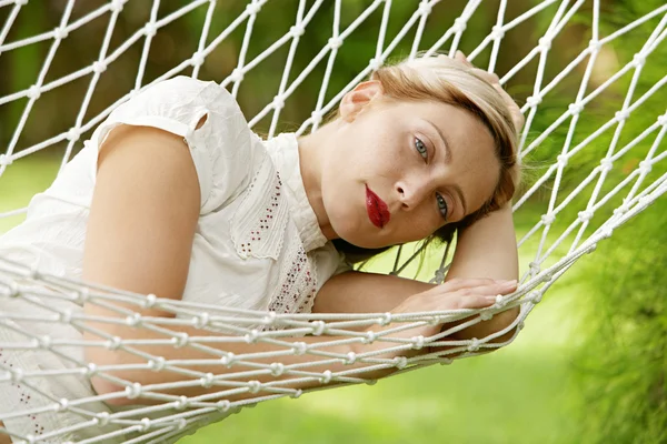 Ung attraktiv kvinna fastställande i en vit hängmatta i en trädgård — Stockfoto
