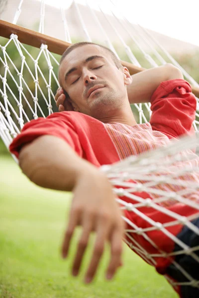 Aantrekkelijke jongeman vaststelling op een netto hangmat — Stockfoto