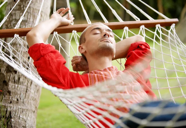 Man laying down on a hammock in a tropical home's garden — Stock Photo, Image