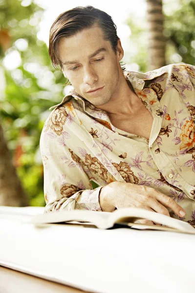 Mladý muž, relaxaci v zahradě a čtení knihy. — Stock fotografie