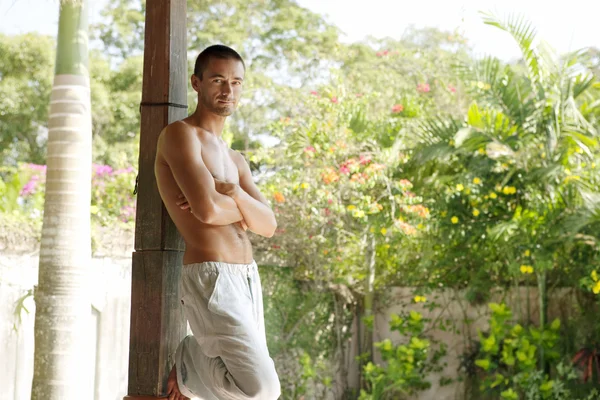 Giovane uomo appoggiato su un palo di legno — Foto Stock