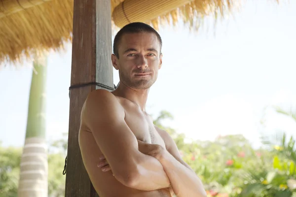 Young man leaning on a wooden pole — Stock Photo, Image