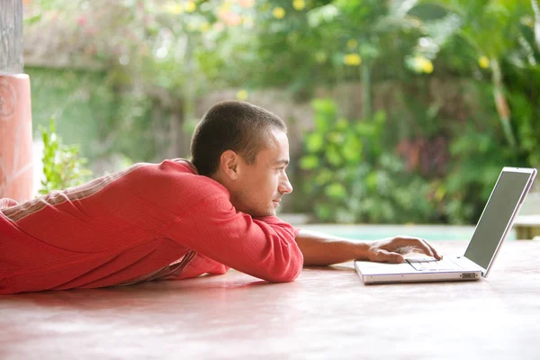 Junger Mann benutzt Laptop, während er sich hinlegt — Stockfoto