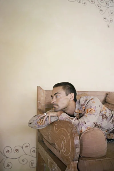 Young man laying down on a sofa being throughful. — Stock Photo, Image