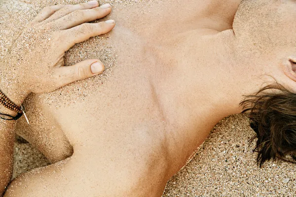 Parte del corpo dettaglio di un uomo prendere il sole su una spiaggia di sabbia dorata — Foto Stock