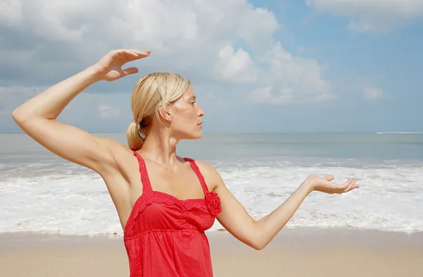 Junge attraktive Frau praktiziert Yoga am Strand. — Stockfoto