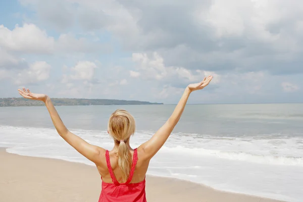 Young woman with her arms outstretched in the air while standing by the shore — Stock Photo, Image