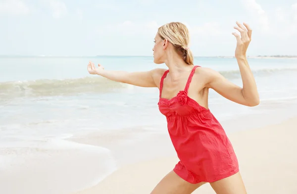 Zijaanzicht van een aantrekkelijke vrouw doet yoga op een tropisch strand. — Stockfoto