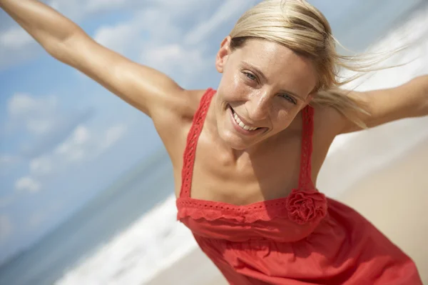 Attraktive blonde Frau am Strand mit ausgestreckten Armen — Stockfoto