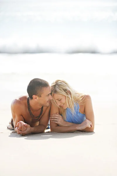 Attractive caucasian couple laying down by the shore being romantic on holiday. — Stock Photo, Image
