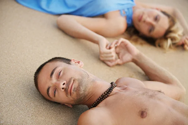 Jovem casal atraente que estabelece na areia dourada — Fotografia de Stock