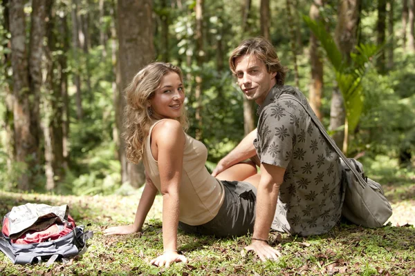 Couple sitting down in a tropical forest. — Stock Photo, Image