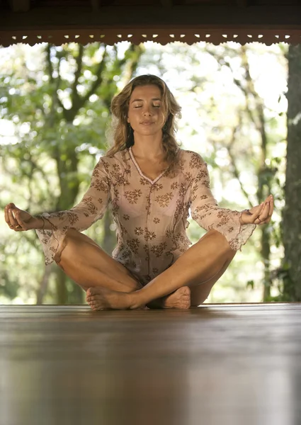 Mulher praticando ioga em uma cabana de madeira na floresta . — Fotografia de Stock