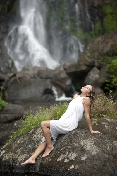 Jeune femme assise près des cascades avec la tête en arrière . — Photo