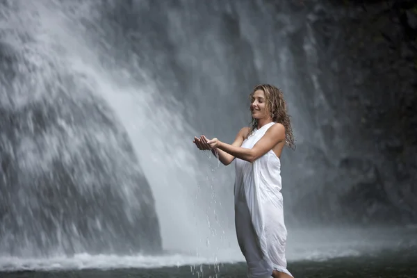 Mujer joven en cascadas, sosteniendo agua en sus manos . — Foto de Stock