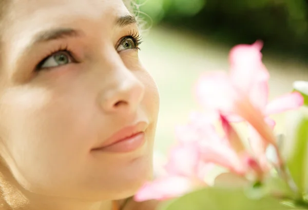 Unga attraktiva flicka att lukta en tropisk rosa blomma — Stockfoto