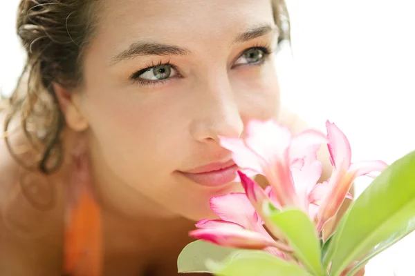 Aantrekkelijk meisje ruiken een tropische roze bloem — Stockfoto