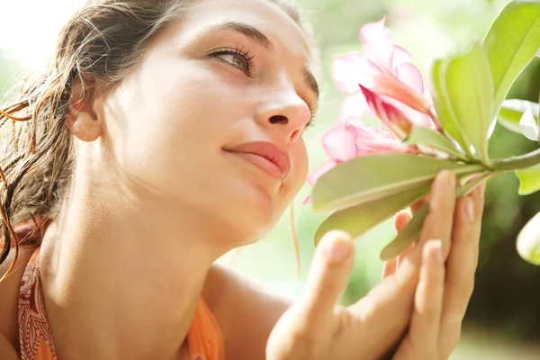 Young attractive girl smelling a tropical pink flower — Stock Photo, Image