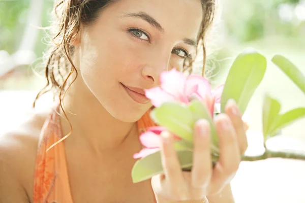 Young attractive girl smelling a tropical pink flower — Stock Photo, Image